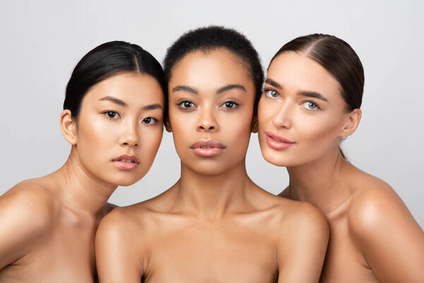 Natural Beauty Concept. Three Pretty Girls Posing Shirtless On Gray Studio Background, Looking At Camera